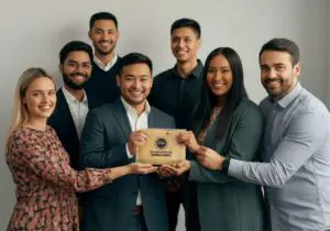 Diverse team of eight in business attire proudly displaying a gold award plaque together in a studio setting, emphasizing recognition, why hotel awards matter.